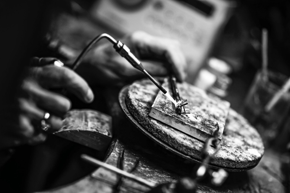 Guldsmed som arbetar med att forma en handgjord vigselring – ett unikt hantverk i skapandet av personliga smycken.