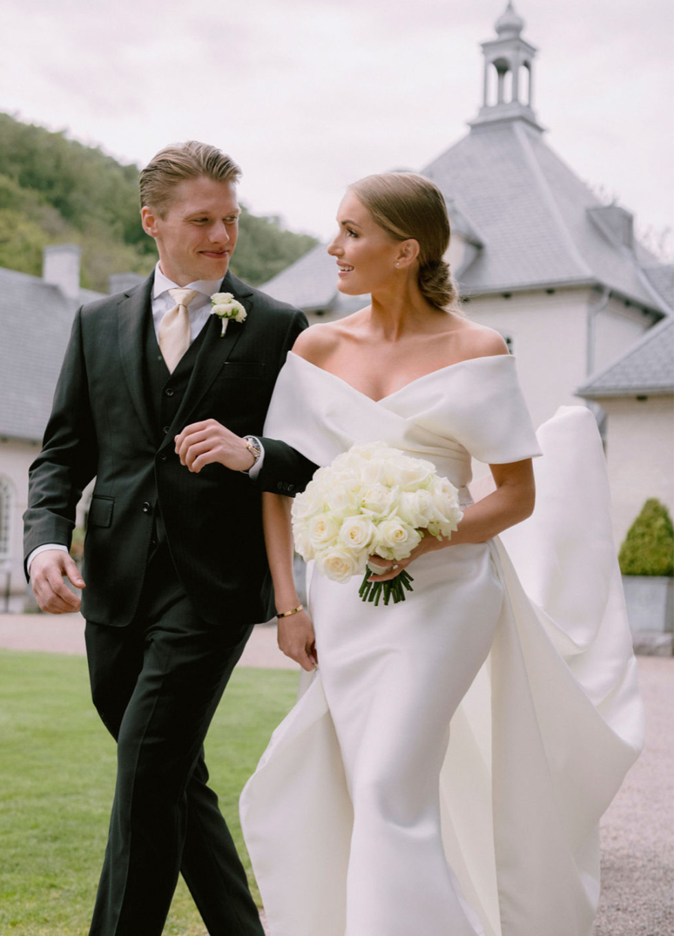 Brudparet poserar romantiskt i de vackra Norrvikens Trädgårdar, omgivna av blomstrande växter och grönska.