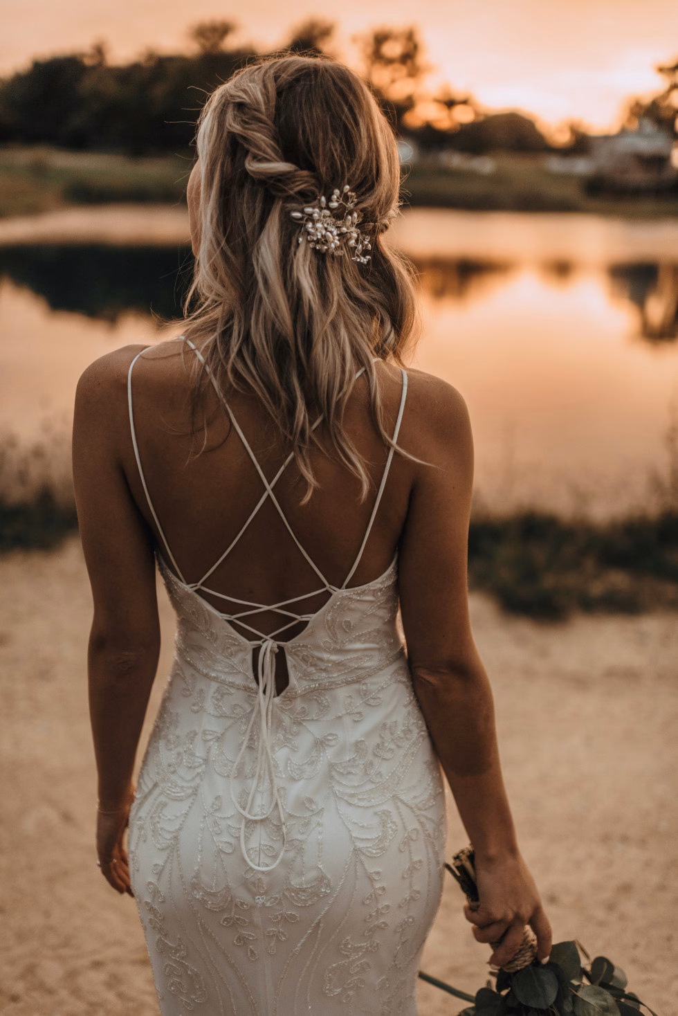 Elegant uppsatt bröllopsfrisyr med lockar och detaljerade blommor – perfekt för en romantisk bröllopslook.