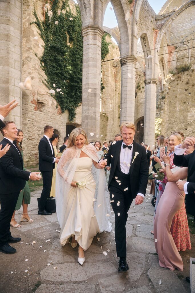 Et nygift par omfavner hverandre i en historisk middelalderkirkeruin i Visby under et bryllup på Gotland