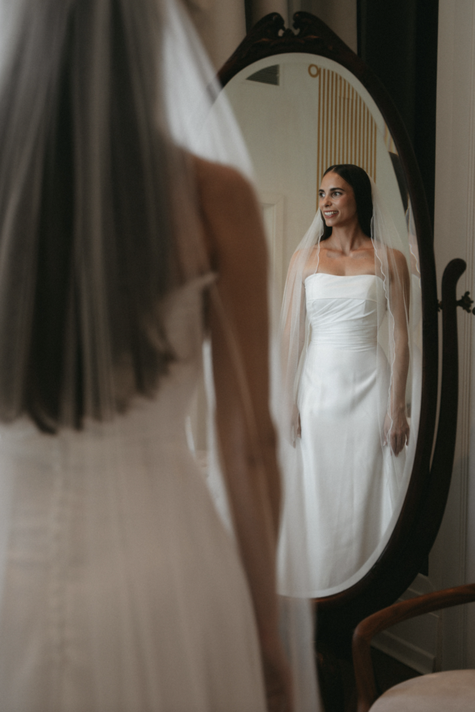 Inspirasjon: Modern Wedding Rules for brudekjole. En brud i hvit kjole ser sitt speilbilde før en moderne vielse.